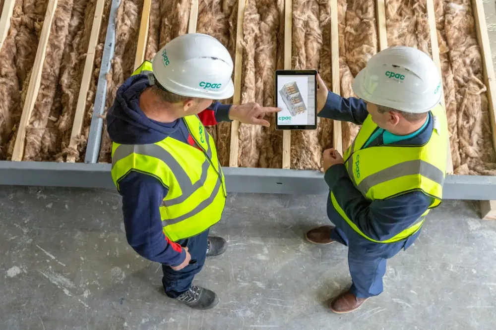 Two construction workers review plans on a tablet, illustrating carpentry qualification assessment